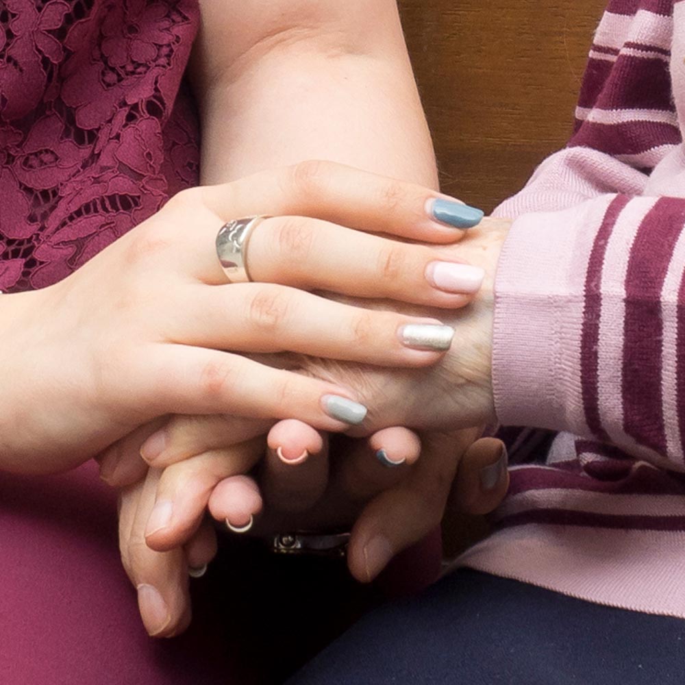 Las manos de dos residentes en las que se ven sus uñas pintadas en la residencia gracias al servicio de manicura y estética que ofrece
